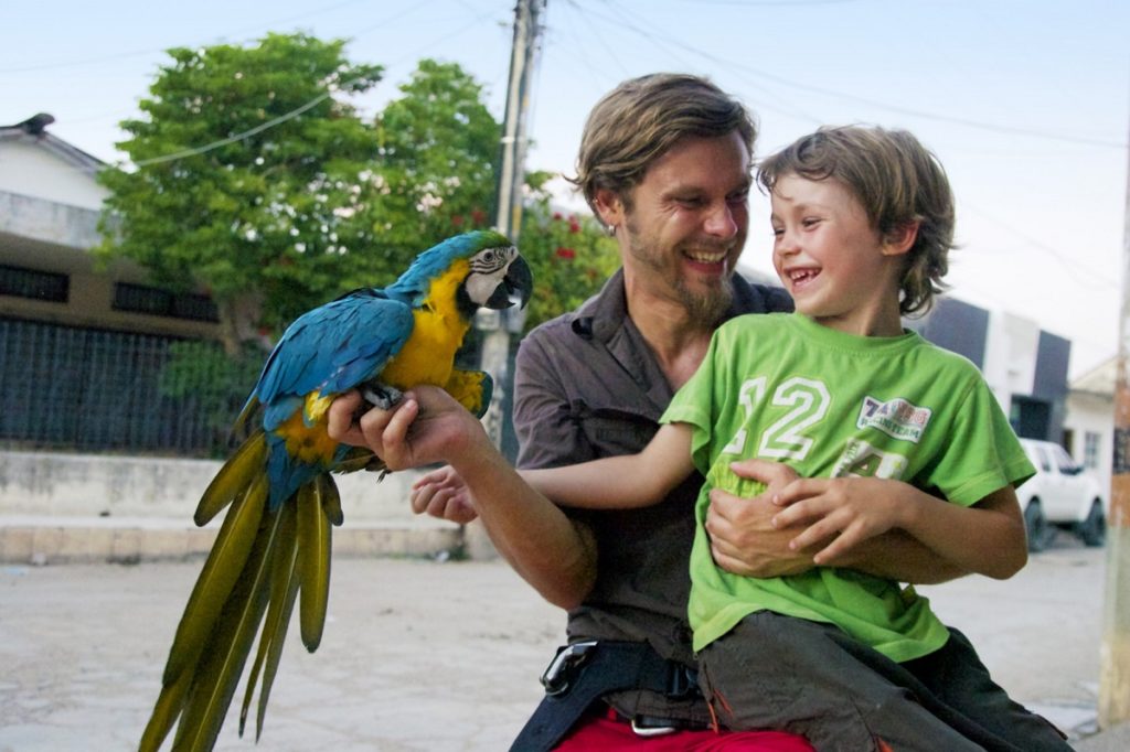 Vater und Sohn auf Tuchfühlung mit einem Papageien in Kolumbien